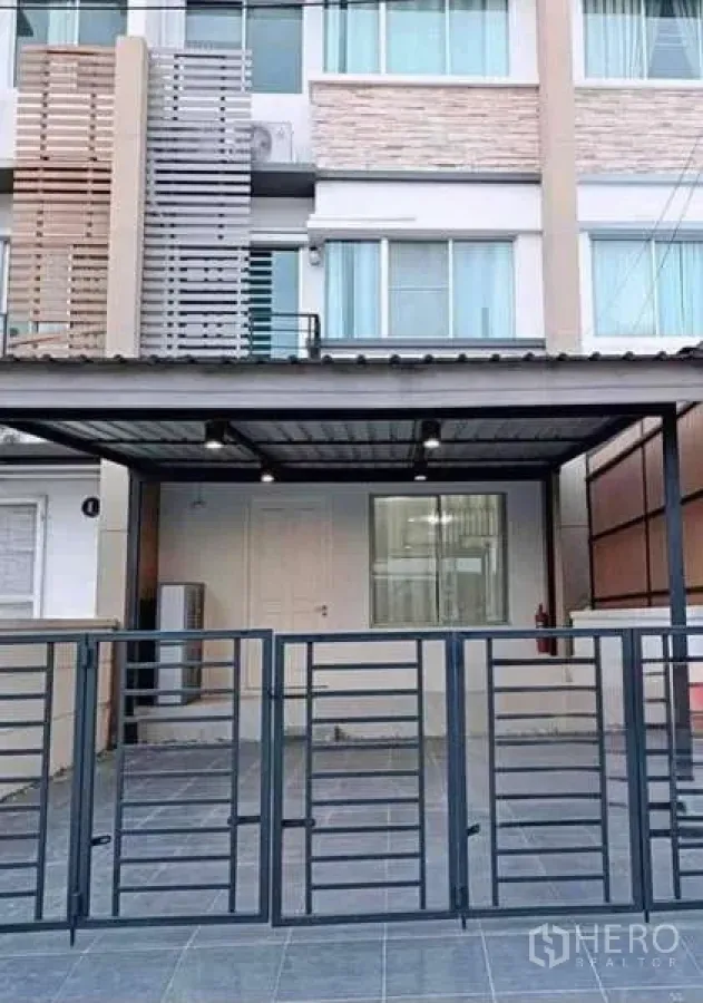 Townhouse for rent in Bang Kapi, Bangkok - Modern three-storey townhouse facade with covered carport and metal gate.