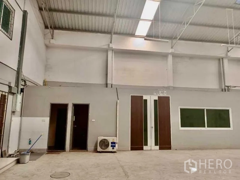 Warehouse for rent in Samut Prakan - Internal office block with doors, large window and wall-mounted AC unit.