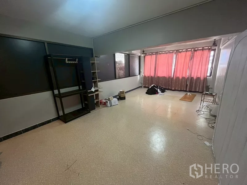 Shophouse for rent in Bang Na, Bangkok - Large upper-floor room with windows and red curtains, open-plan layout and shelving.