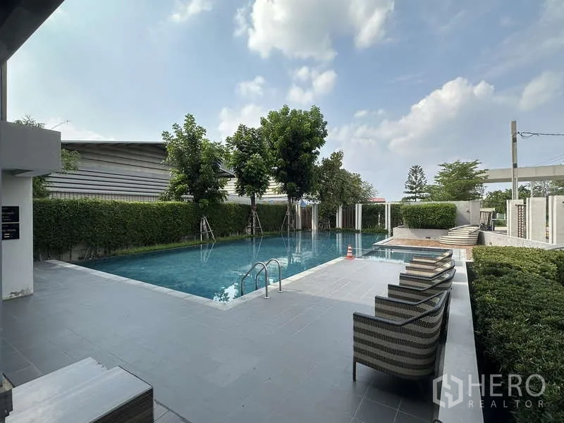 独立式住宅 出售在Sai Mai, Bangkok - 小区住户泳池，带躺椅与绿篱。