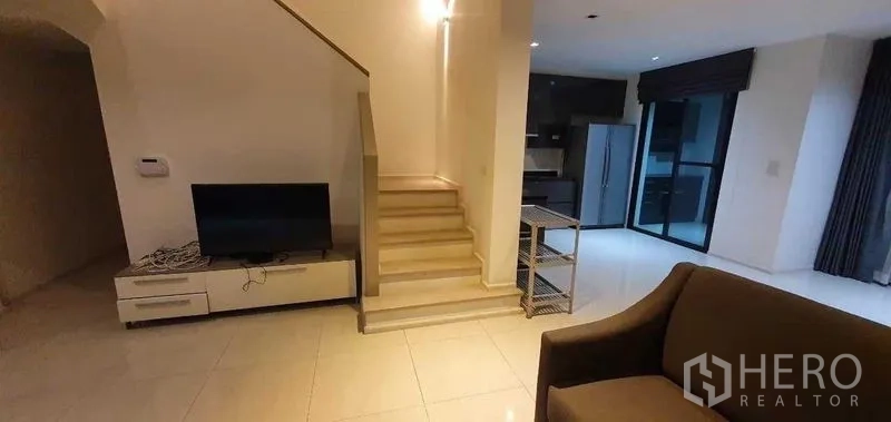 Detached House for rent in Prawet, Bangkok - Open-plan living area with staircase, TV console and access to the kitchen