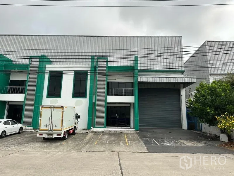 Factory for rent or sale in Bang Phli, Samut Prakan - Modern green-and-white factory facade in Bang Phli with roller shutter, loading bay, and parking.