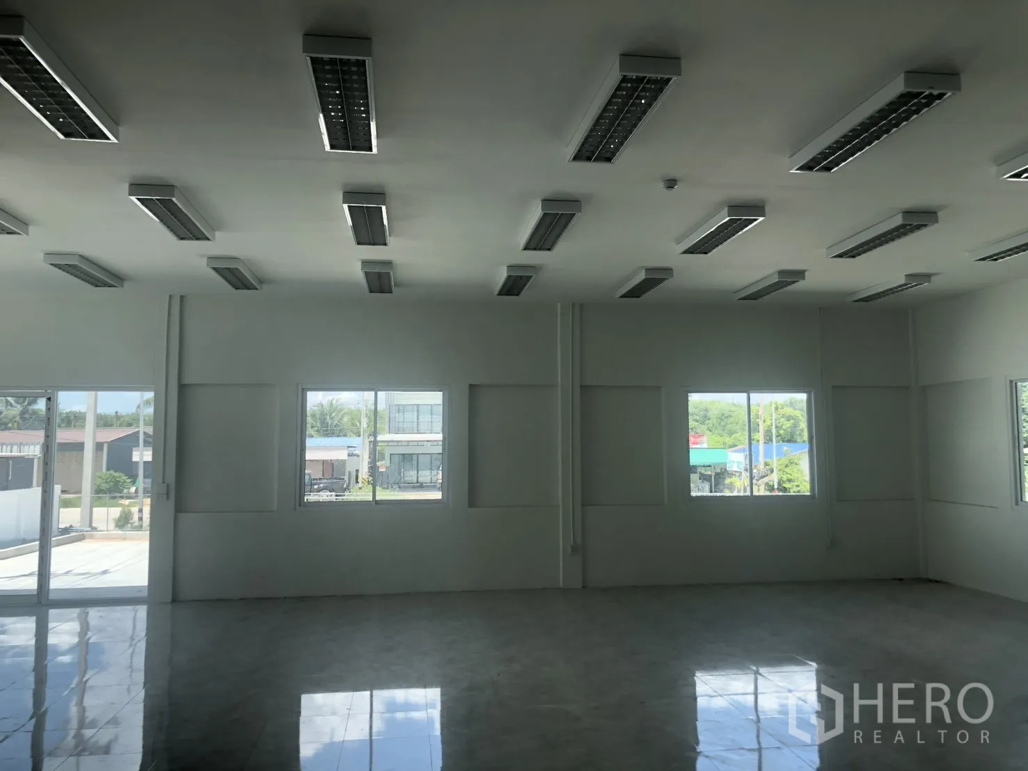 Factory for rent in Si Racha, Chon Buri - Bright office room with tiled floor, multiple ceiling light fixtures, and windows.