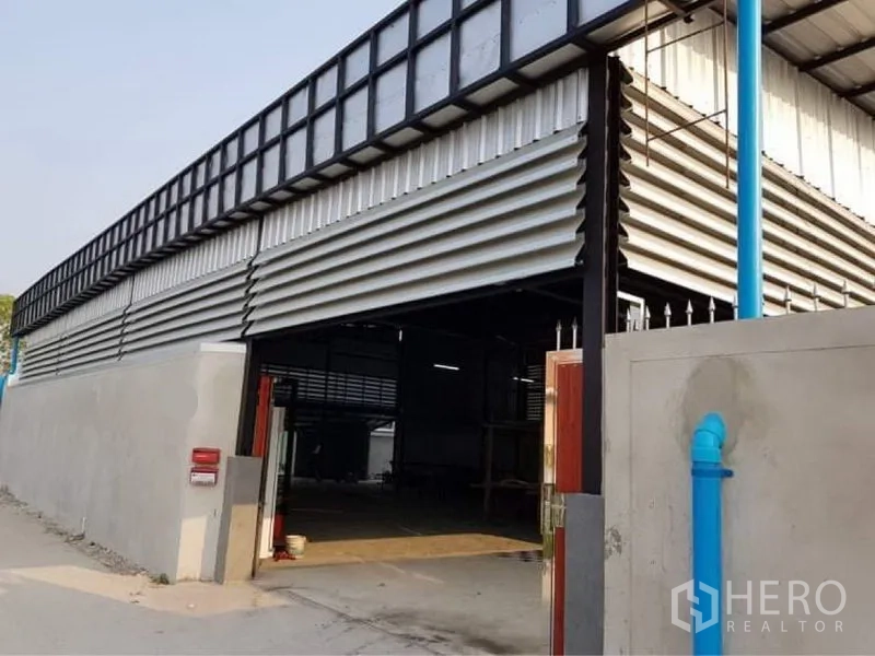 Warehouse for sale in Lam Luk Ka, Pathum Thani - Main gate partially open, showing drive-in access to the warehouse.