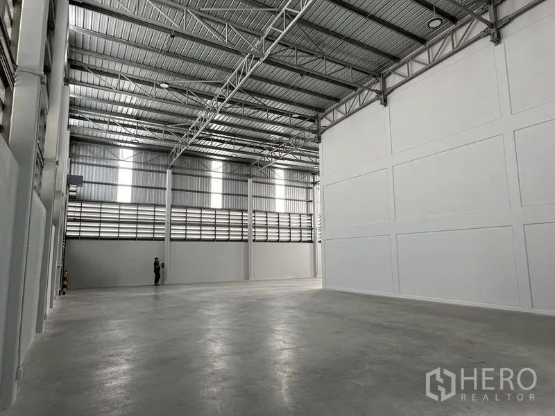 Warehouse for rent in Bang Phli, Samut Prakan - Open storage hall with high metal roof, ventilation louvers, and smooth concrete floor.