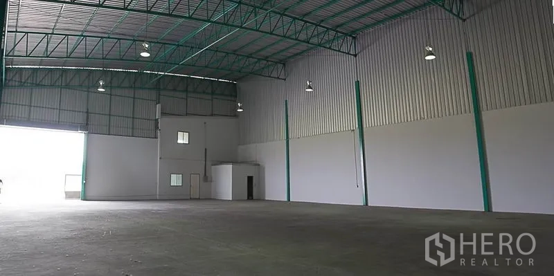 Warehouse for rent in Khlong Luang, Pathum Thani - Spacious high-ceiling warehouse interior with steel trusses, smooth concrete floor and large roller door.
