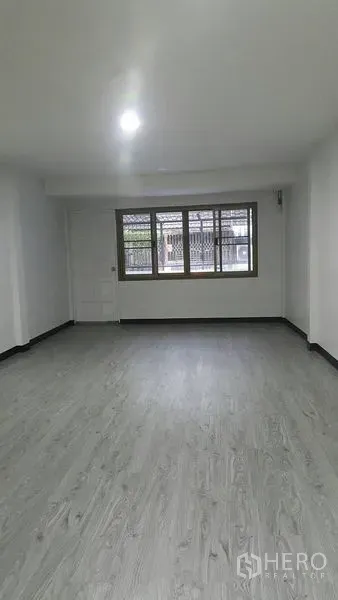 Shophouse for rent in Watthana, Bangkok - Spacious upper-floor room with large front windows and bright ceiling light.