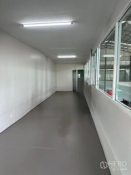 Warehouse for rent in Lat Krabang, Bangkok - Mezzanine office corridor with windows overlooking the warehouse floor and bright LED lighting.