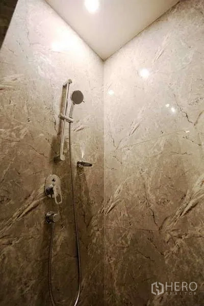 Condominium for rent in Watthana, Bangkok - Marble-tiled shower with handheld and rain fixtures under recessed lighting.