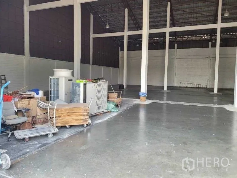 Warehouse for rent in Phra Khanong, Bangkok - Open storage area with concrete floor and equipment carts to the side