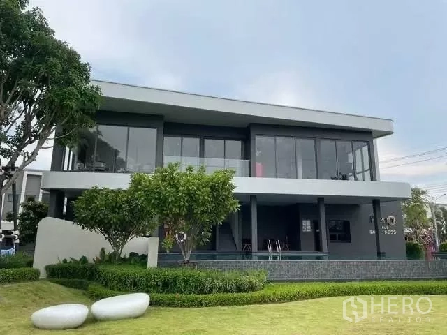 Townhouse for rent in Bang Phli, Samut Prakan - Community clubhouse with modern glass facade and landscaped lawns.