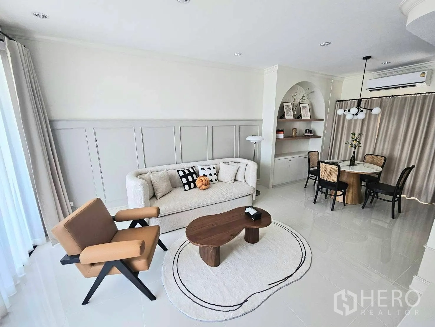 Townhouse for rent in Saphan Sung, Bangkok - Bright living room in Bangkok townhouse with white sofa, tan armchair, round rug, wood coffee table, and a dining nook.