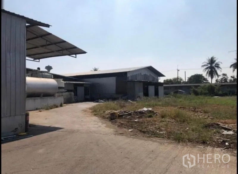 工厂 出租在Bang Khla, Chachoengsao - 工业区开放式水泥场地，金属厂棚、储罐与周边绿化。