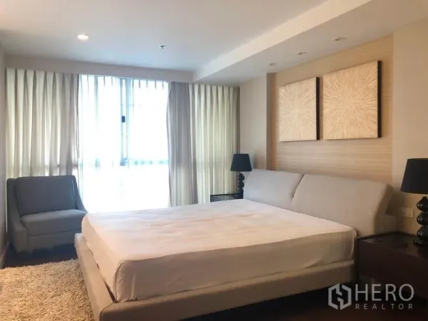Condominium for rent in Pathum Wan, Bangkok - Spacious bedroom with king bed, artwork and floor-to-ceiling curtains.