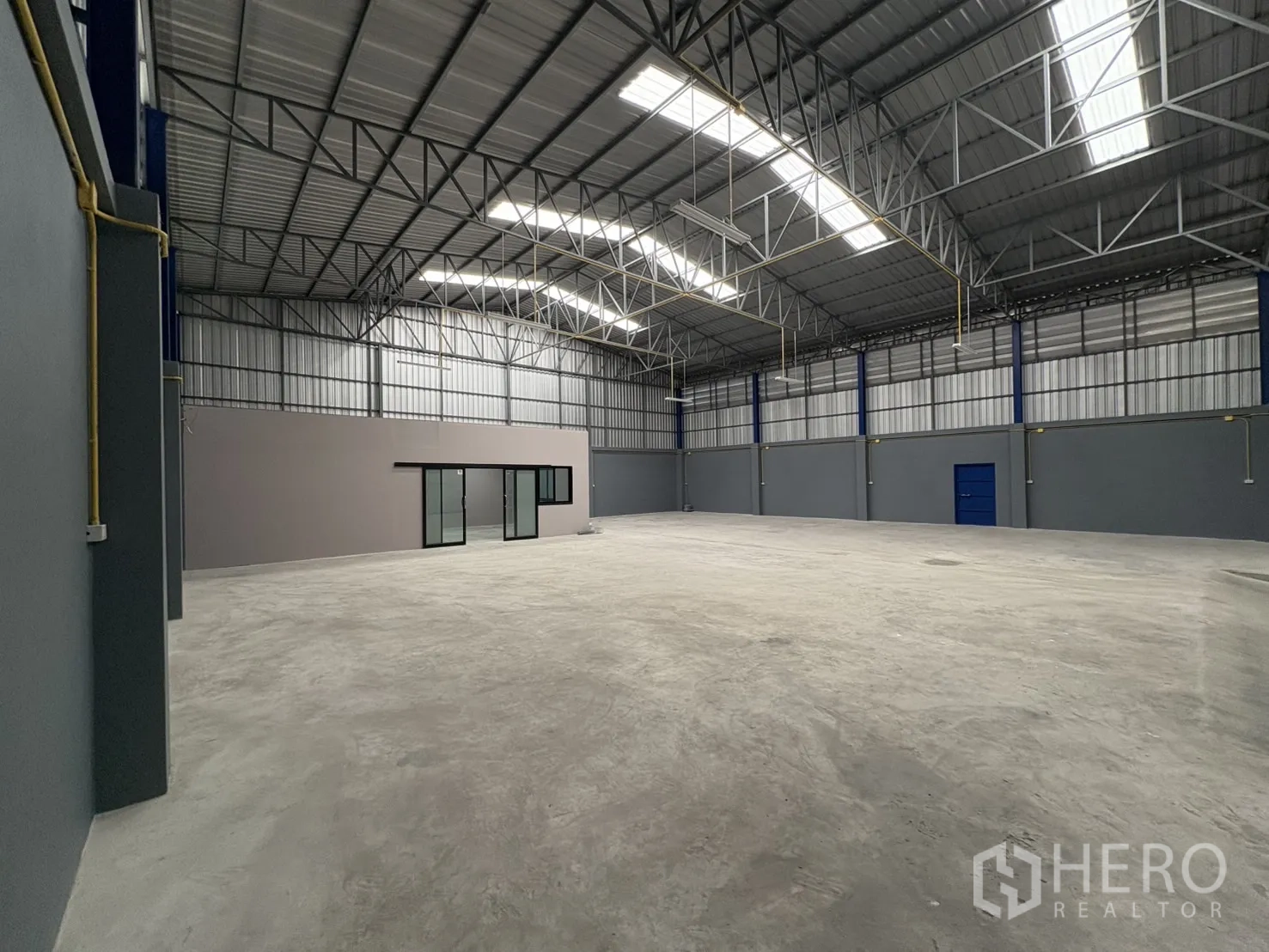 Warehouse for rent in Bang Phli, Samut Prakan - Panoramic view of the empty warehouse floor beneath a ventilated metal roof with skylight panels.