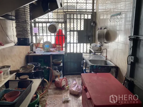 Shophouse for rent in Khlong Toei, Bangkok - Rear kitchen with stainless sink, gas stoves and metal security door.