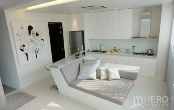 Townhouse for rent in Watthana, Bangkok - Sleek white kitchen with built-in appliances and an island lounge seat.