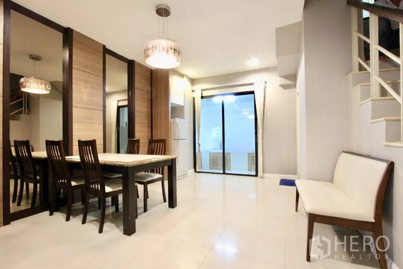 Townhouse for sale in Suan Luang, Bangkok - Dining zone with mirror feature wall, pendant light, and access to terrace.
