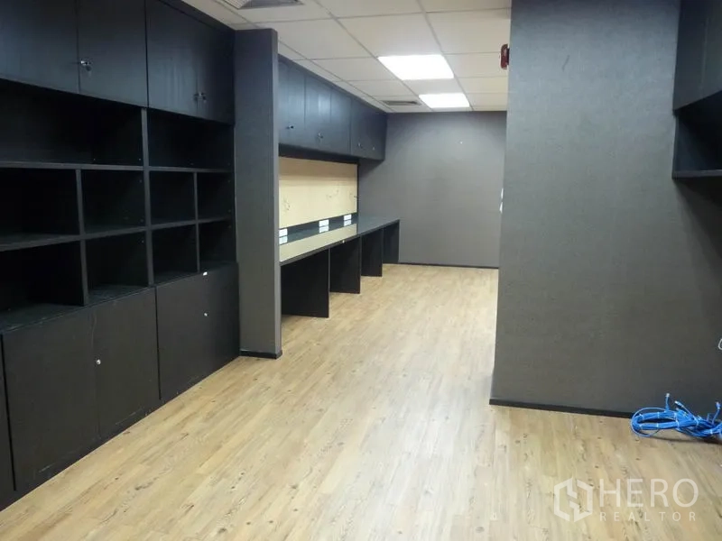 Office Space for rent in Watthana, Bangkok - Workroom fitted with black open shelving, long built-in desks and wood flooring.
