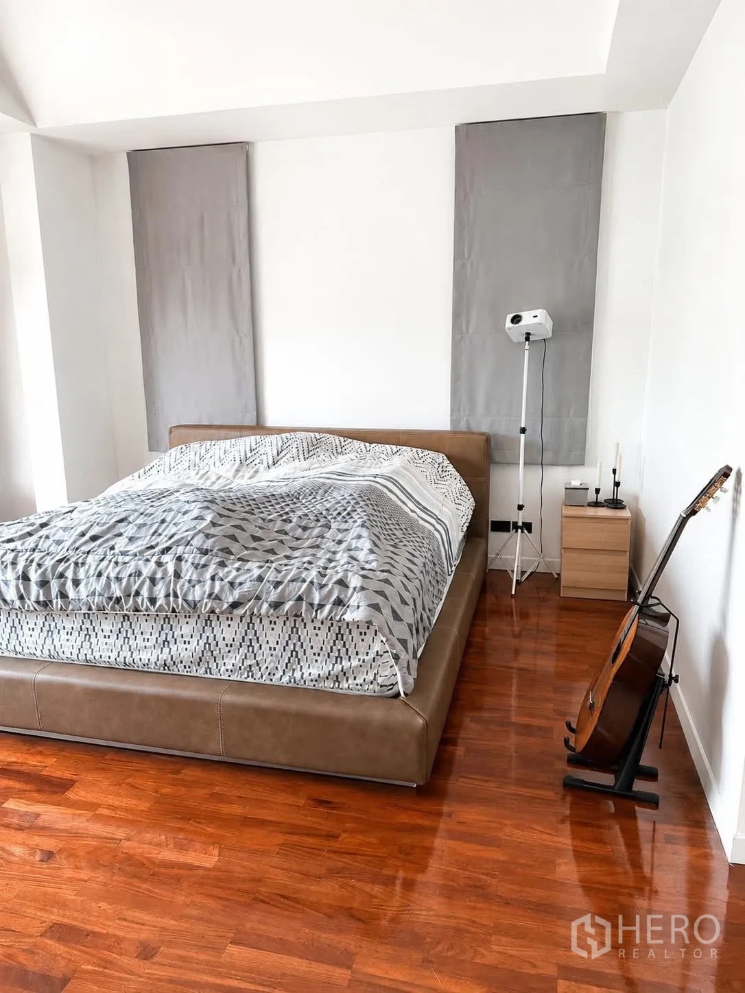 Detached House for rent in Prawet, Bangkok - Minimalist bedroom with low platform bed, guitar stand, and polished wood flooring.