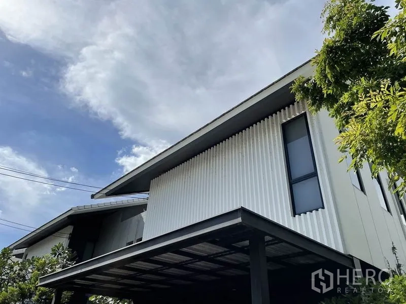 Detached House for sale in Sai Mai, Bangkok - Close-up of the modern façade showing corrugated cladding and a metal carport roof.