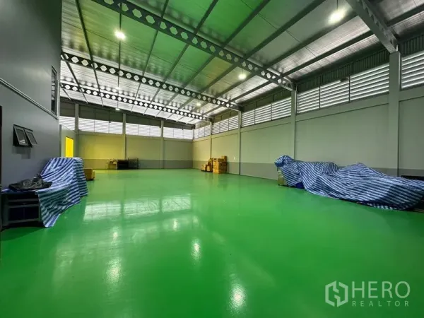 Factory for rent or sale in Lam Luk Ka, Pathum Thani - Spacious production hall with glossy green epoxy floor, steel truss roof and louvered ventilation.