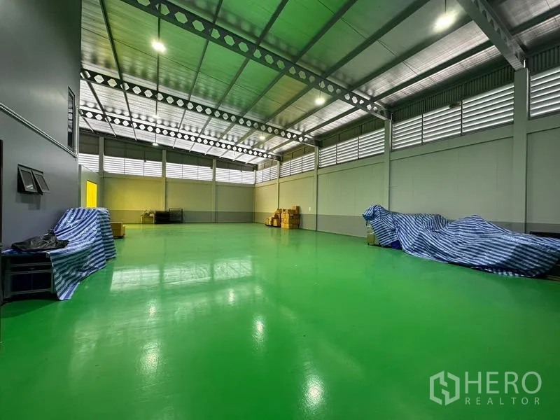 Factory for rent or sale in Lam Luk Ka, Pathum Thani - Spacious production hall with glossy green epoxy floor, steel truss roof and louvered ventilation.