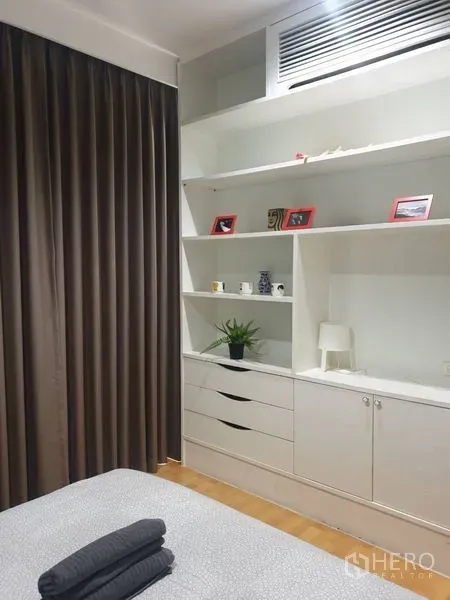 Condominium for rent in Khlong Toei, Bangkok - Bedroom corner featuring white built-in cabinets, drawers, and decorative shelving.
