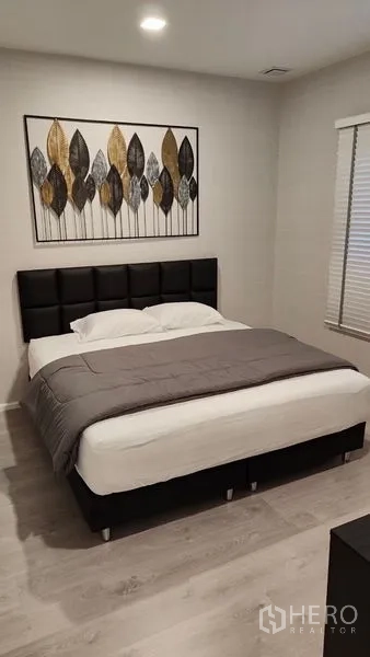 Detached House for rent in Prawet, Bangkok - Guest bedroom with upholstered headboard, soft bedding and framed wall art.
