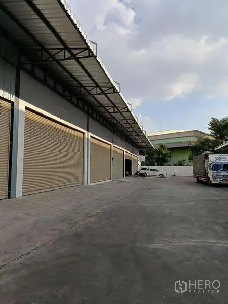 Warehouse for rent in Khlong Toei, Bangkok - Covered loading dock with multiple roller doors and a wide yard for trucks.