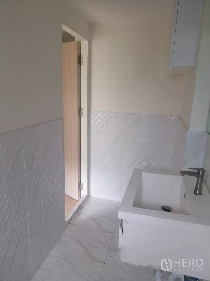 Retail Space for rent - Bathroom corridor with white tiles and vanity leading to a wooden door.