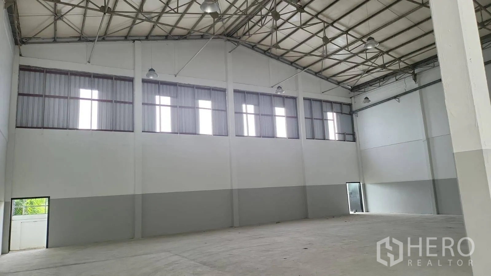 Factory for rent in Bang Phli, Samut Prakan - Spacious warehouse hall with high steel truss roof, clerestory windows and bright lighting.