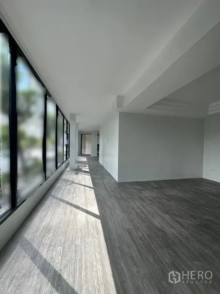 Retail Space for rent in Bang Rak, Bangkok - Sunlit open‑plan retail interior with full‑length windows and grey wood‑look flooring.