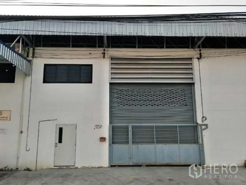 Factory for rent in Bang Phli, Samut Prakan - Factory exterior with large roll-up shutter door, ventilation louvers, and gated loading bay in Samut Prakan.