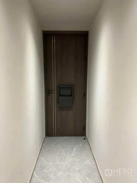 Condominium for rent in Pathum Wan, Bangkok - Entrance corridor leading to a dark wood front door with gray tile floor.
