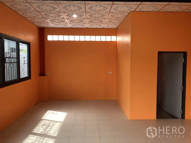 Warehouse for rent in Nonthaburi - Bright office area with tiled floor, window security bars and doorway to a restroom.