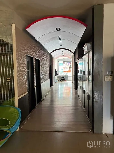 Retail Space for rent - Long corridor with arched ceiling and side rooms leading toward a glass frontage.