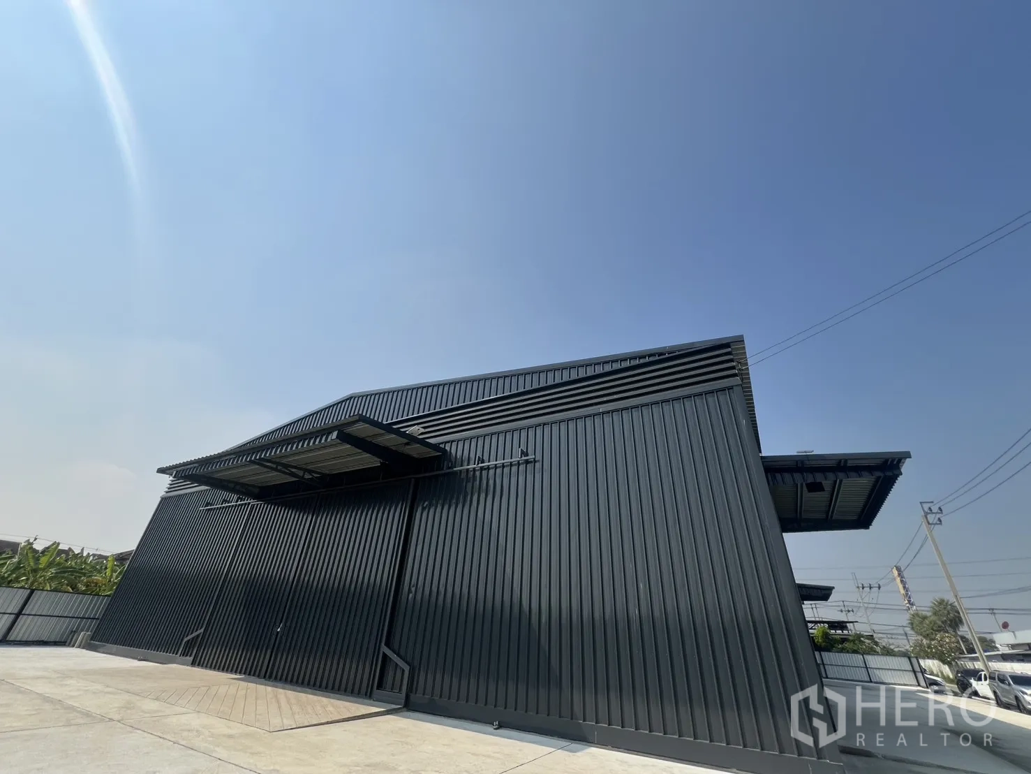 Warehouse for rent in Lat Krabang, Bangkok - Low-angle facade of a high-roof warehouse with louvered ventilation and a covered dock.