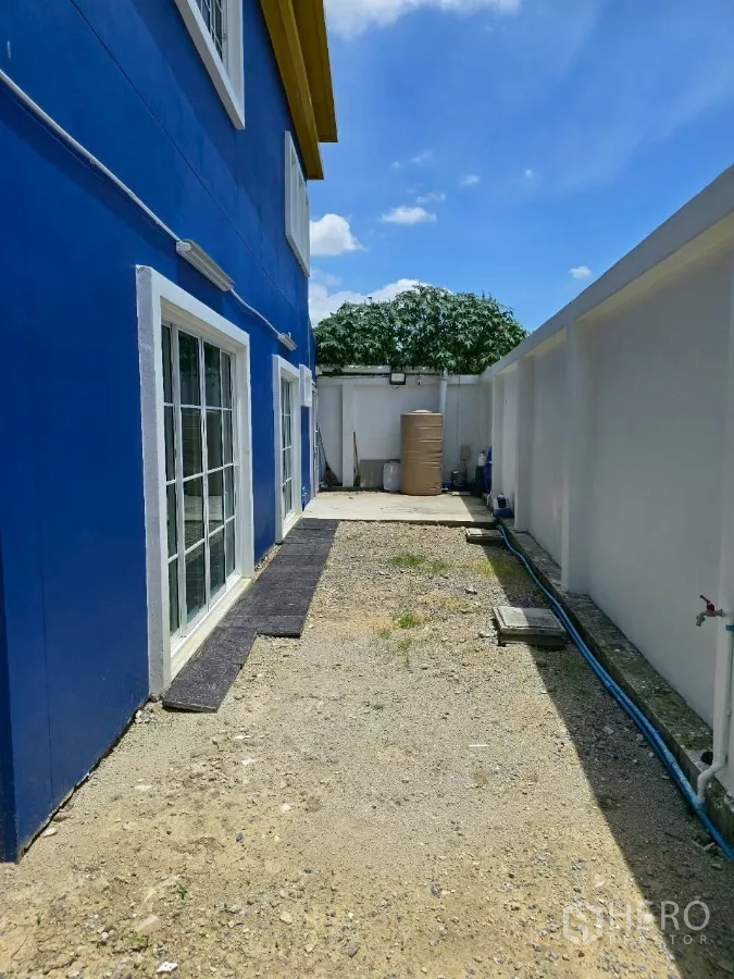 Warehouse for rent or sale in Khlong Toei, Bangkok - Side garden and service area with sliding glass doors and a water tank behind the building.