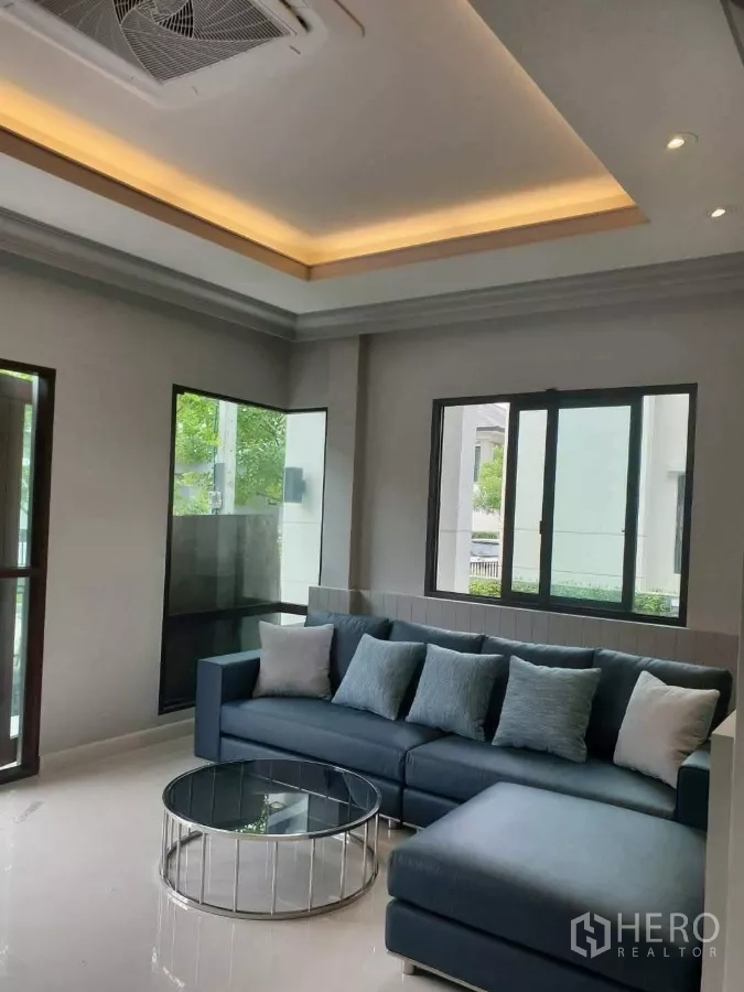 Detached House for rent or sale in Prawet, Bangkok - Cozy family lounge with L-shaped sofa, large windows and recessed lighting