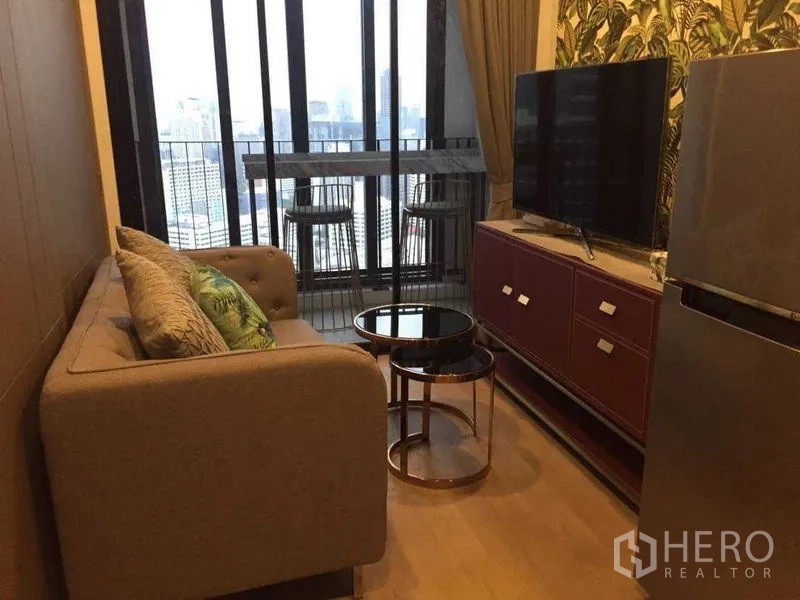Condominium for rent in Bang Rak, Bangkok - Living area with sofa, nesting tables and TV facing the balcony bar.