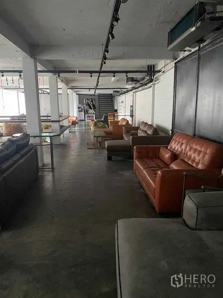 Retail Space for rent in Bang Na, Bangkok - Long showroom corridor with leather sofas, track lighting and polished concrete floor.