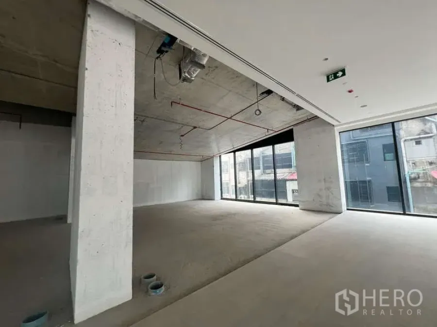 Retail Space for rent - Open-plan 90 sqm retail unit with exposed concrete ceiling, ducting and floor-to-ceiling windows in Phaya Thai near BTS Sanam Pao.