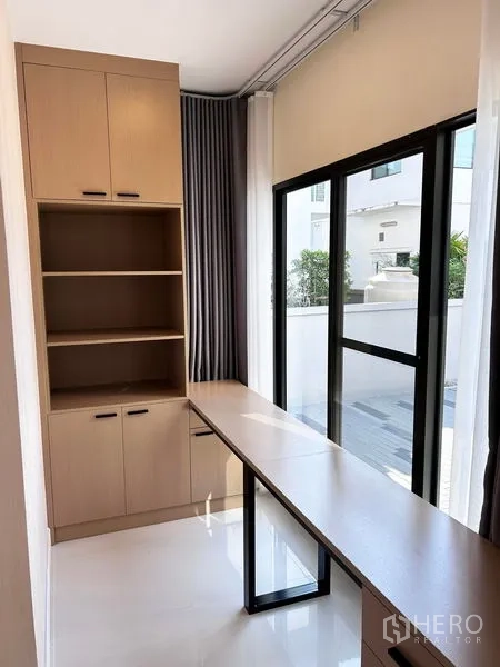 Detached House for rent or sale in Prawet, Bangkok - Sunlit study nook with long built-in desk and storage cabinets.