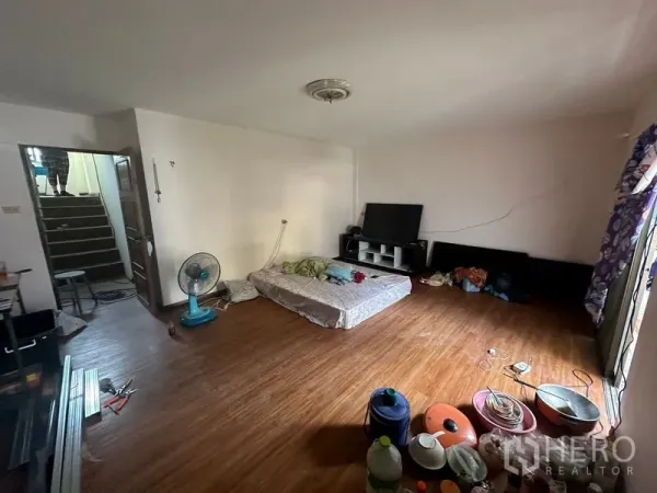 Home Office for rent in Sathon, Bangkok - Spacious living room with wood flooring, TV cabinet and stair access, ideal for a bedroom or lounge.