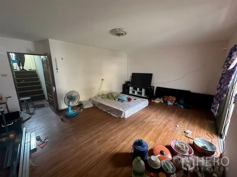 Home Office for rent in Sathon, Bangkok - Spacious living room with wood flooring, TV cabinet and stair access, ideal for a bedroom or lounge.