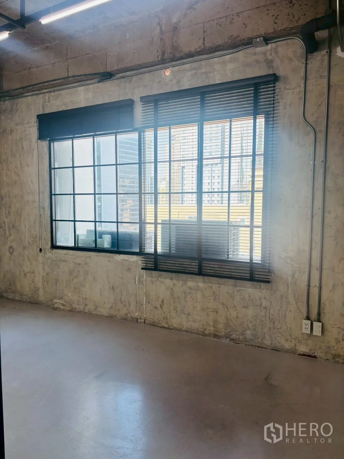 办公空间 出租在Khlong Toei, Bangkok - 采光充足的工作区，宽窗与城市景观，混凝土墙面