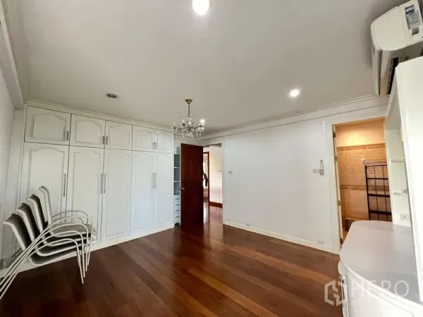 Detached House for rent in Chatuchak, Bangkok - Bedroom with chandelier, wall-to-wall closets and doorway to the bathroom.
