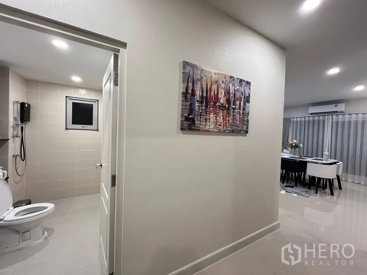 Detached House for rent in Prawet, Bangkok - Hallway with view into a tiled bathroom with shower and an open-plan dining area beyond.
