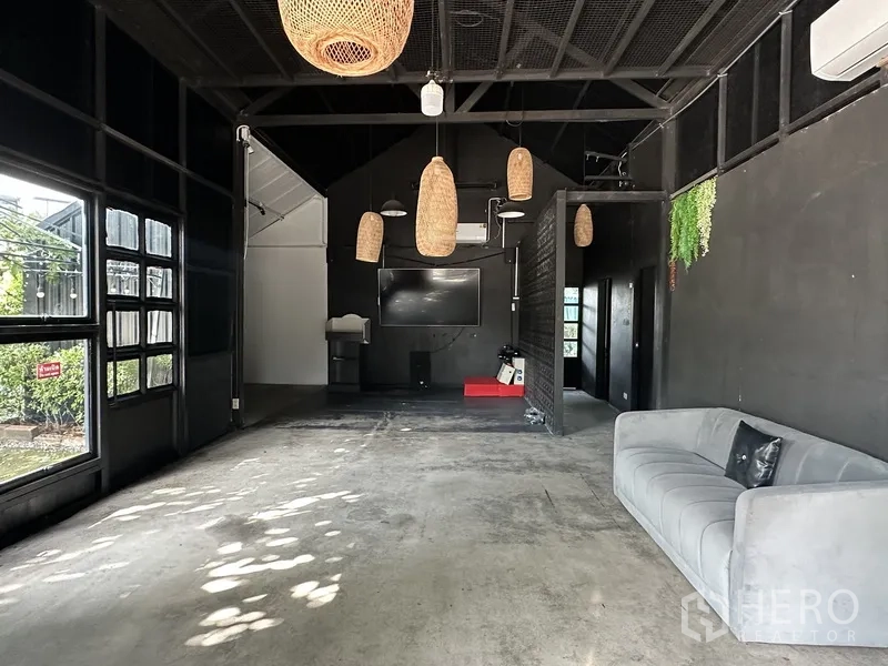 พื้นที่ขายของ for rent in Phra Khanong, Bangkok - ภายในโล่งมีโซฟาสีเทา โคมแขวน ทีวี และพื้นคอนกรีต